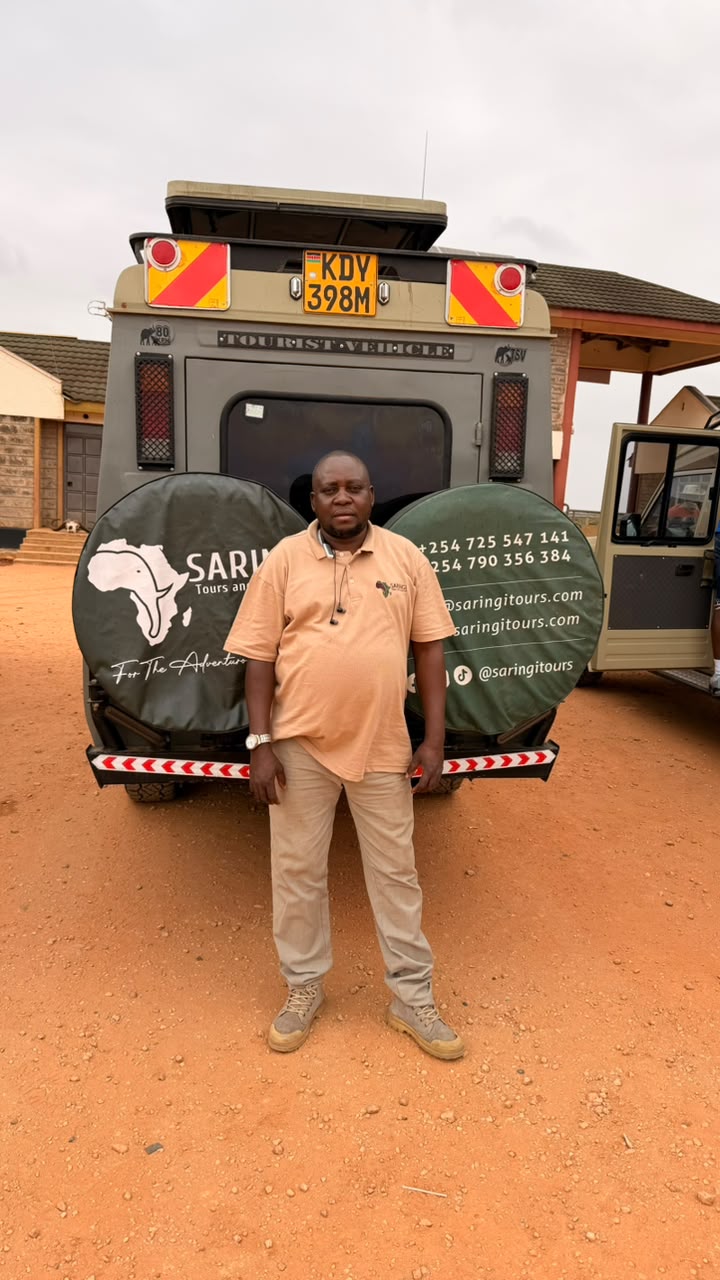Saringi Tours guide standing beside a branded safari vehicle in the field